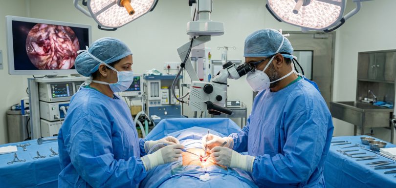 Indian spine surgeons performing microsurgical spinal tumor resection with surgical operating microscope